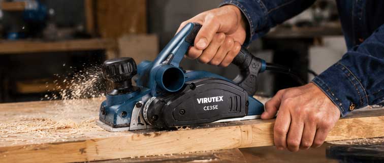 Operario utilizando el cepillo VIRUTEX CE35E sobre una tabla de madera en taller de carpintería